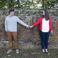 Newly engaged couple posing for a picture holding hands