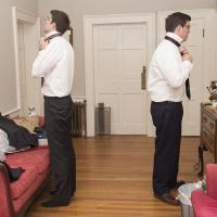 Groom and best man getting ready for wedding by putting on ties