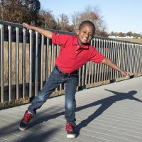 Young boy posing for a picture balancing on one foot and hands out