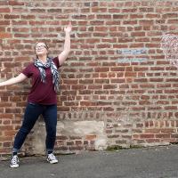 Young female posing for senior picture on location with arms in the air