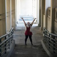 Young female posing for senior picture on location with hands in the air