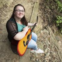 Young female posing for senior picture on location with guitar